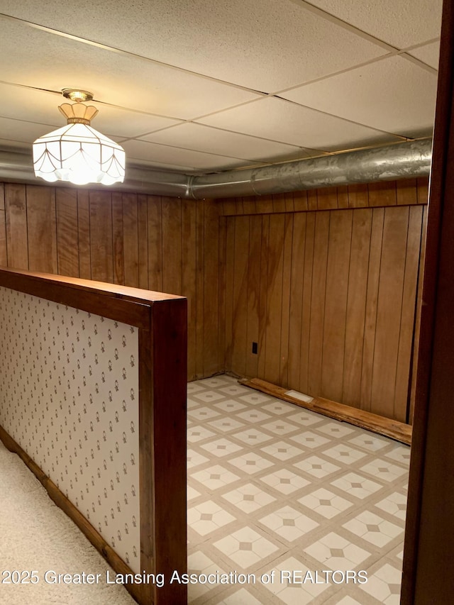 3156 E M-21 Rd, Saint Johns, MI 48879 - finished below grade area with a paneled ceiling, baseboards, wood walls, and light floors