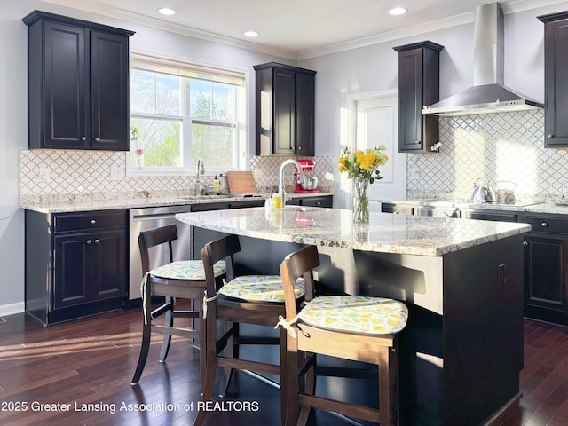 2718 Kittansett Dr, Okemos, MI 48864 - kitchen with wall chimney range hood, stainless steel dishwasher, dark wood-style floors, a center island, and light stone counters