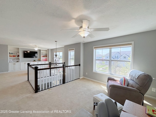 2718 Kittansett Dr, Okemos, MI 48864 - living room featuring light colored carpet, a ceiling fan, baseboards, a textured ceiling, and built in features