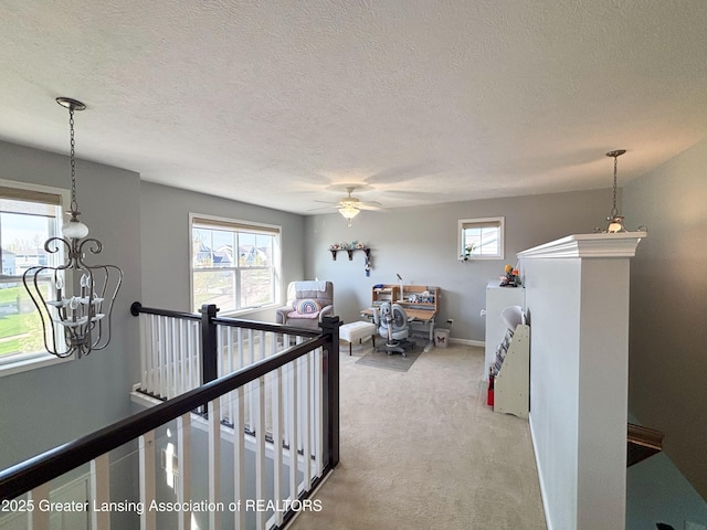 2718 Kittansett Dr, Okemos, MI 48864 - hall with an upstairs landing, light colored carpet, a textured ceiling, baseboards, and a chandelier