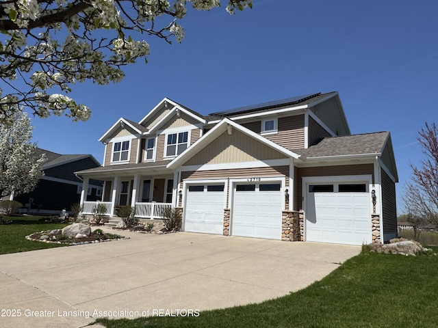 2718 Kittansett Dr, Okemos, MI 48864 - craftsman-style home with covered porch, a garage, stone siding, driveway, and a front lawn