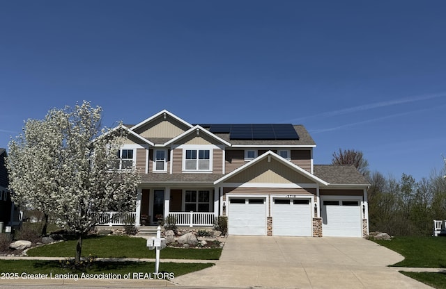2718 Kittansett Dr, Okemos, MI 48864 - craftsman-style home with covered porch, driveway, roof mounted solar panels, a front lawn, and an attached garage