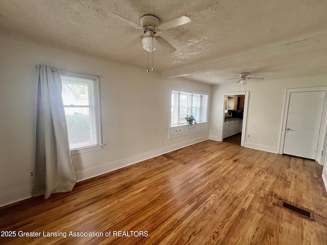 empty room with visible vents, a ceiling fan, and a textured ceiling