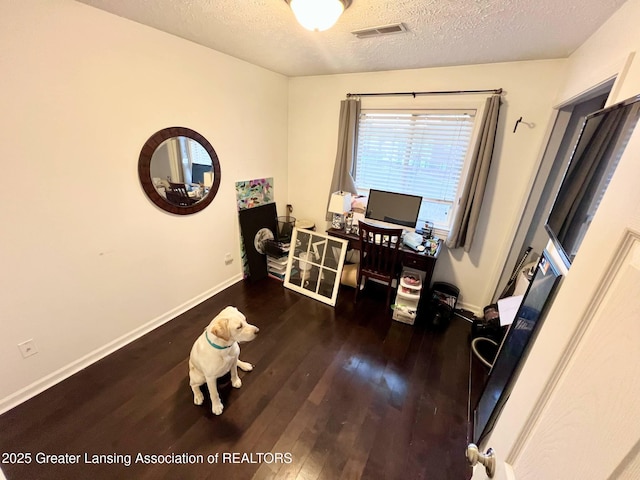office with baseboards, visible vents, hardwood / wood-style flooring, and a textured ceiling
