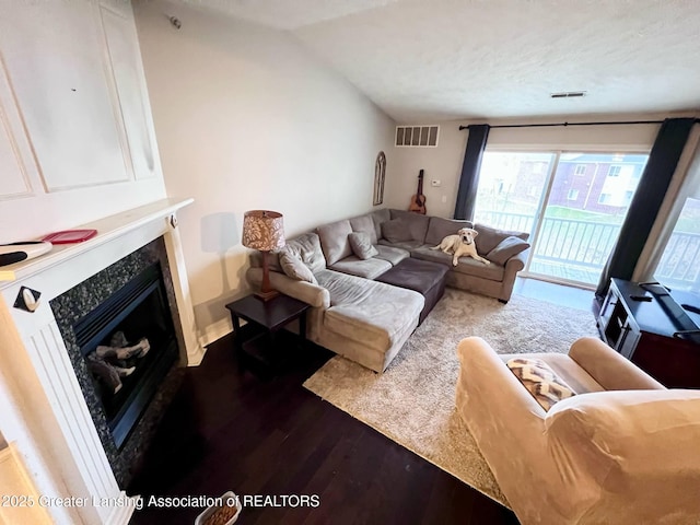 living room featuring visible vents, vaulted ceiling, wood finished floors, and a fireplace