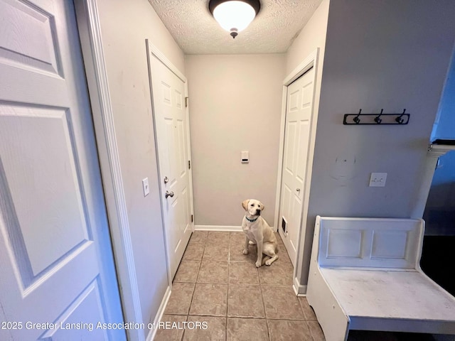 laundry room featuring baseboards, light tile patterned floors, and a textured ceiling
