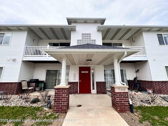 view of exterior entry with covered porch and brick siding