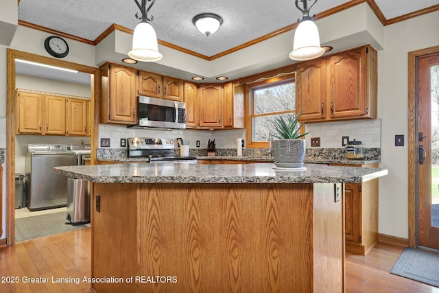 11267 Jarvis Hwy, Dimondale, MI 48821 - kitchen featuring washer and dryer, crown molding, light wood finished floors, stainless steel appliances, and decorative backsplash