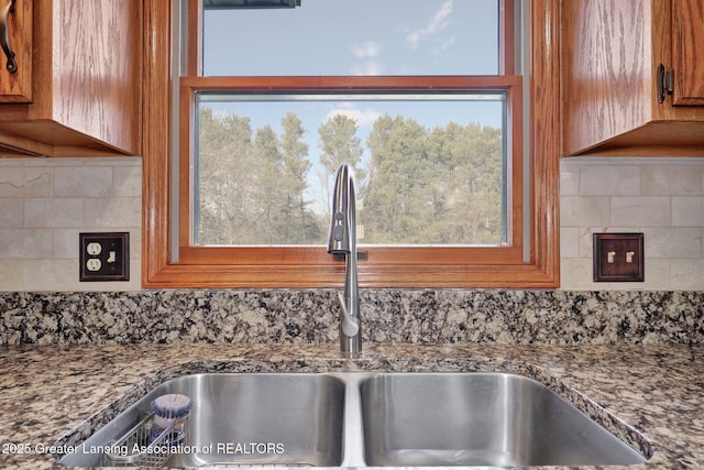 11267 Jarvis Hwy, Dimondale, MI 48821 - room details featuring brown cabinets, decorative backsplash, a sink, and dark stone counters
