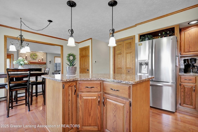 11267 Jarvis Hwy, Dimondale, MI 48821 - kitchen with a kitchen island, crown molding, hanging light fixtures, stainless steel fridge with ice dispenser, and light wood finished floors