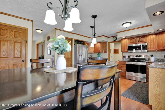 11267 Jarvis Hwy, Dimondale, MI 48821 - kitchen featuring an inviting chandelier, a textured ceiling, light wood-style flooring, appliances with stainless steel finishes, and backsplash