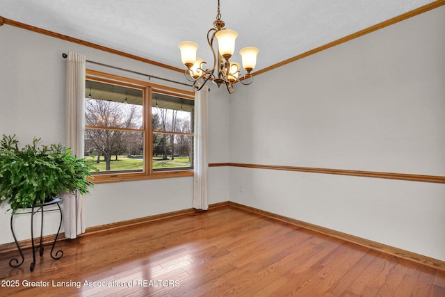 11267 Jarvis Hwy, Dimondale, MI 48821 - empty room with wood-type flooring, crown molding, a notable chandelier, and baseboards