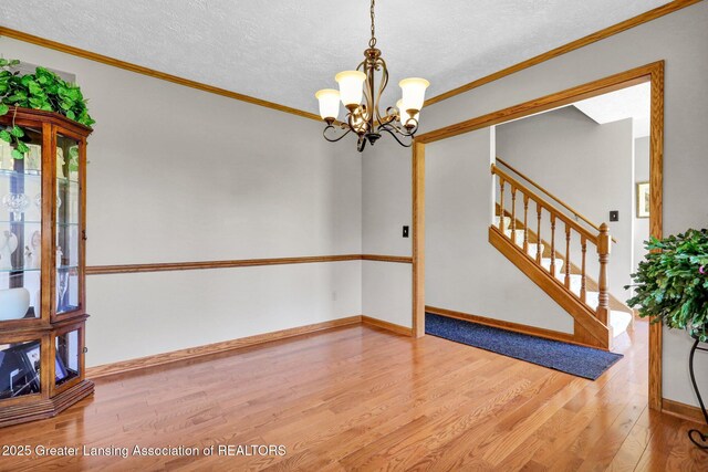 11267 Jarvis Hwy, Dimondale, MI 48821 - unfurnished room with crown molding, a textured ceiling, wood finished floors, and a chandelier