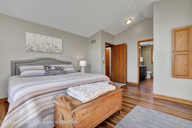 11267 Jarvis Hwy, Dimondale, MI 48821 - bedroom featuring visible vents, wood finished floors, baseboards, connected bathroom, and vaulted ceiling
