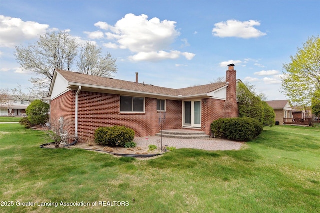 back of property with brick siding, roof with shingles, a yard, and a chimney