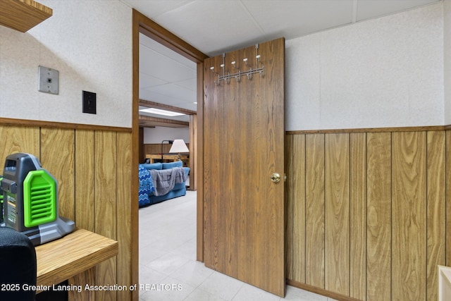 hall featuring wooden walls and a wainscoted wall