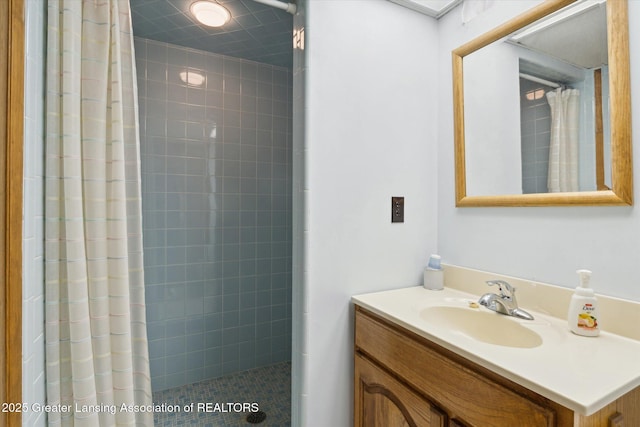 full bath featuring tiled shower and vanity