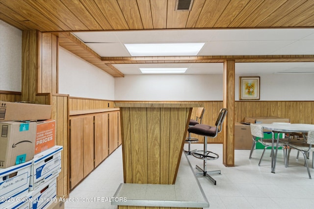 interior space featuring light floors, wooden walls, and wainscoting