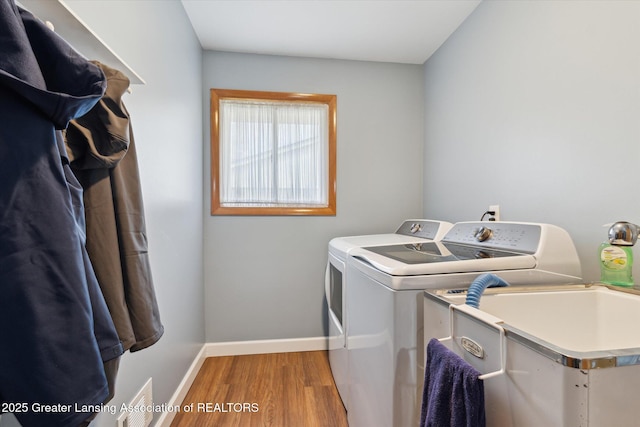 laundry room featuring baseboards, wood finished floors, separate washer and dryer, and laundry area