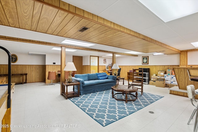 living area with a wainscoted wall, visible vents, wood walls, and tile patterned floors