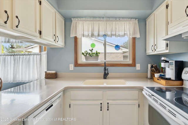 kitchen featuring a wealth of natural light, white appliances, light countertops, and a sink