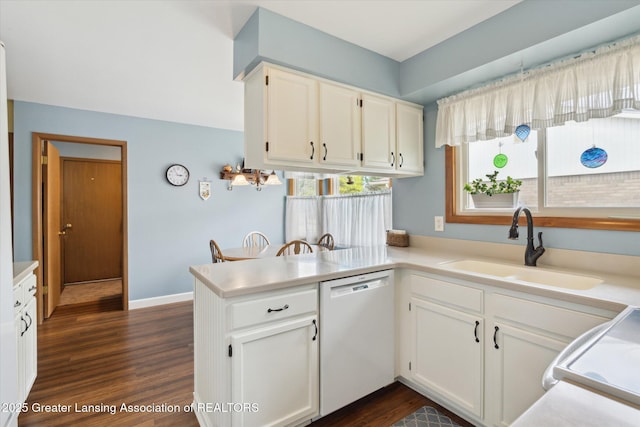 kitchen featuring white cabinets, a sink, dishwasher, dark wood-type flooring, and a peninsula