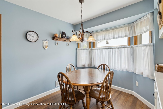 dining space featuring an inviting chandelier, wood finished floors, and baseboards