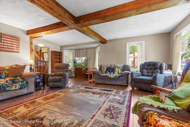 living room with hardwood / wood-style floors, plenty of natural light, beam ceiling, and stairway