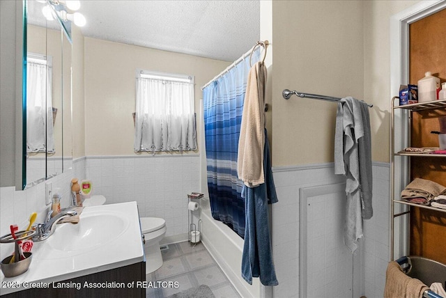 bathroom with tile walls, a wainscoted wall, toilet, vanity, and tile patterned floors