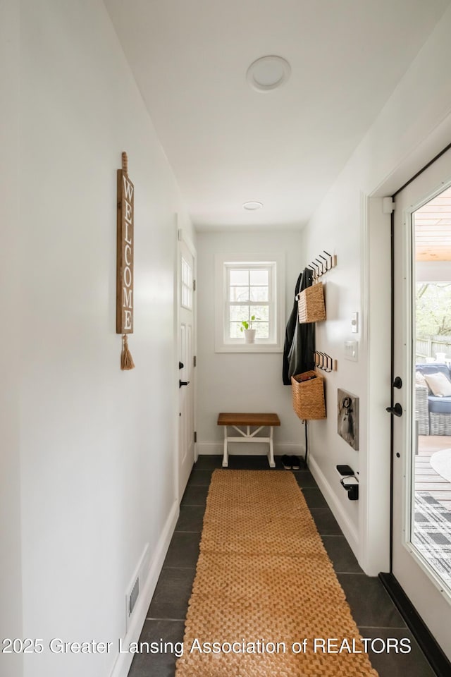 mudroom with visible vents, baseboards, and dark tile patterned flooring