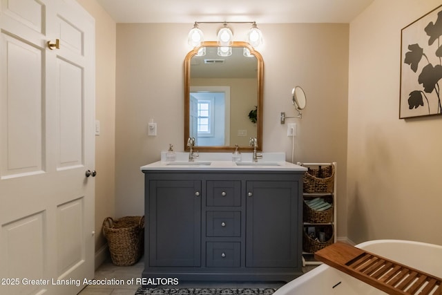 bathroom with double vanity, visible vents, a soaking tub, and a sink
