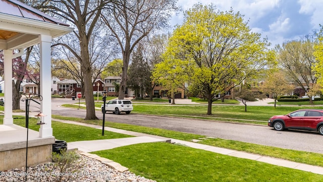 view of street with curbs, sidewalks, a residential view, and traffic signs