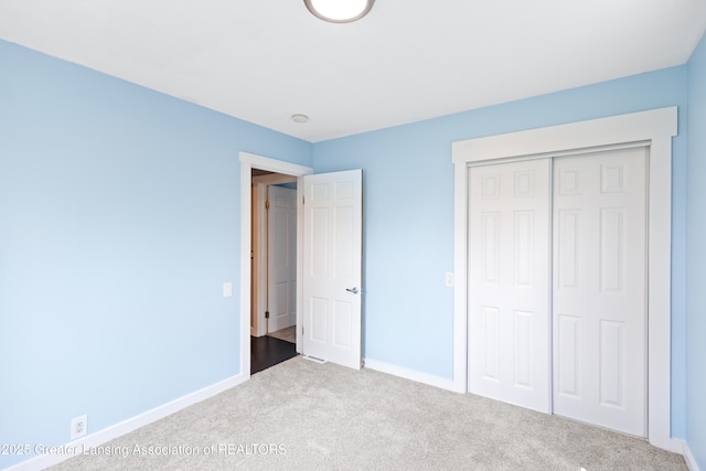 unfurnished bedroom with baseboards, carpet flooring, and a closet