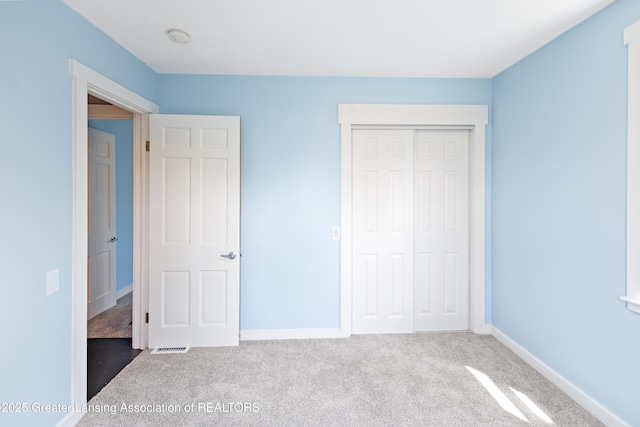 unfurnished bedroom featuring a closet, baseboards, and carpet flooring