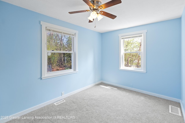 empty room featuring baseboards, ceiling fan, carpet flooring, and visible vents