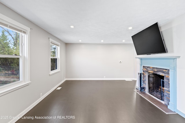 unfurnished living room with baseboards, recessed lighting, a stone fireplace, and wood finished floors