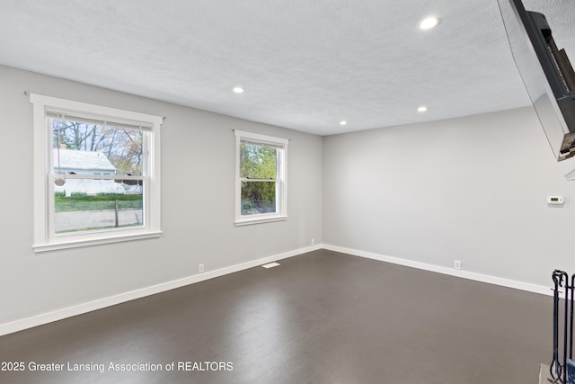 spare room featuring recessed lighting, baseboards, dark wood-type flooring, and a textured ceiling