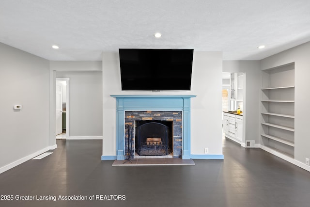 unfurnished living room with recessed lighting, a fireplace with raised hearth, built in features, and baseboards