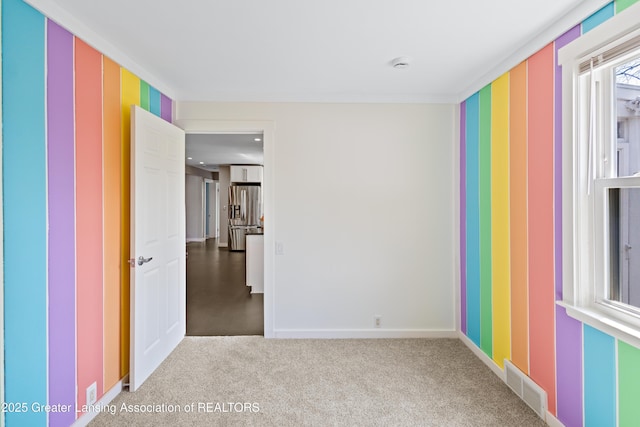 carpeted empty room featuring visible vents, baseboards, and wallpapered walls