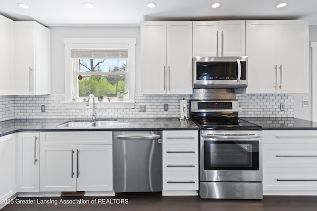 kitchen featuring white cabinets, a sink, stainless steel appliances, recessed lighting, and backsplash