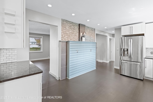 kitchen with backsplash, white cabinetry, stainless steel fridge with ice dispenser, and dark stone countertops