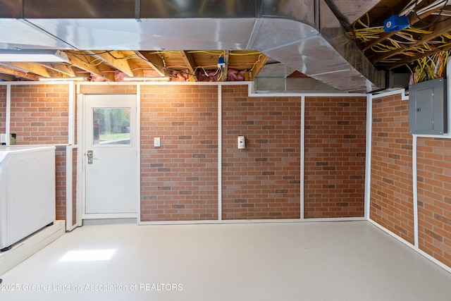 basement with washer / clothes dryer, electric panel, and brick wall