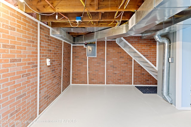 unfinished below grade area with electric panel and brick wall