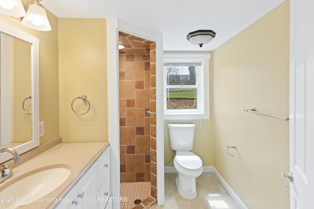 bathroom with vanity, tile patterned floors, a tile shower, and toilet