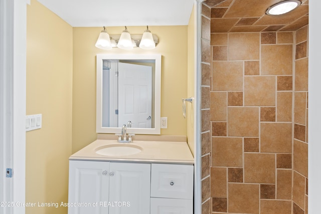 full bathroom featuring a tile shower and vanity