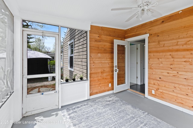 interior space with wood walls, finished concrete flooring, and a ceiling fan