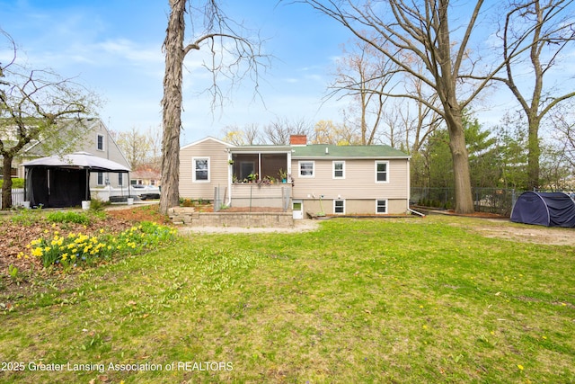 back of house featuring a sunroom, fence, a yard, and a chimney