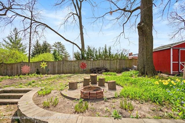 view of yard featuring a fenced backyard, a storage unit, an outdoor structure, and a fire pit