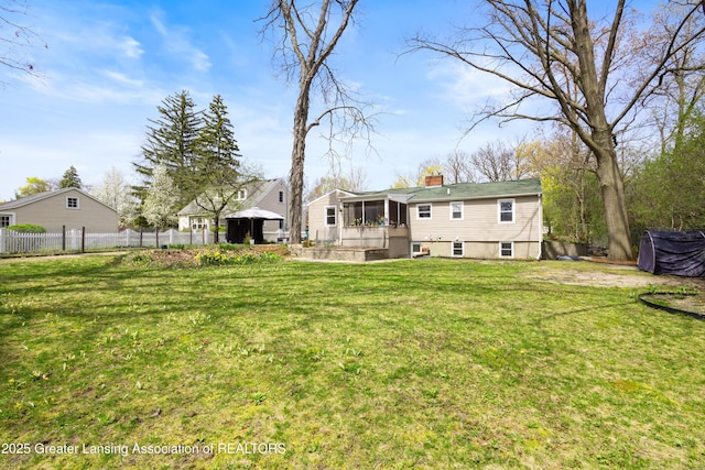 back of property with fence, a chimney, a sunroom, a gazebo, and a yard