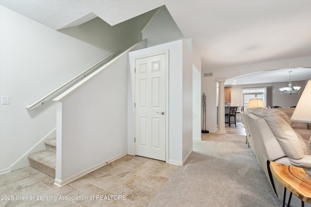 interior space with ornate columns, an inviting chandelier, stairs, visible vents, and baseboards